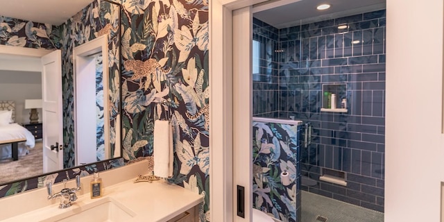 ensuite bathroom featuring tiled shower, ensuite bathroom, vanity, and wallpapered walls