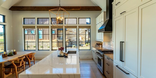 kitchen featuring a sink, beamed ceiling, wall chimney exhaust hood, and high end stainless steel range