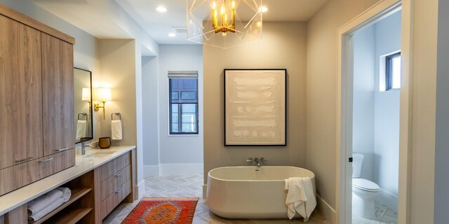 bathroom featuring a freestanding tub, baseboards, toilet, and vanity