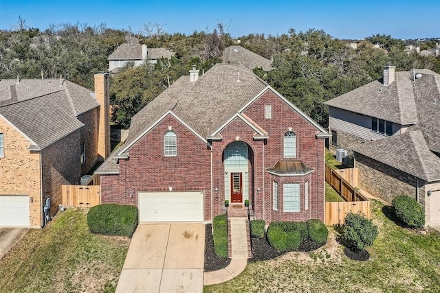 traditional home featuring a gate, fence, brick siding, and driveway