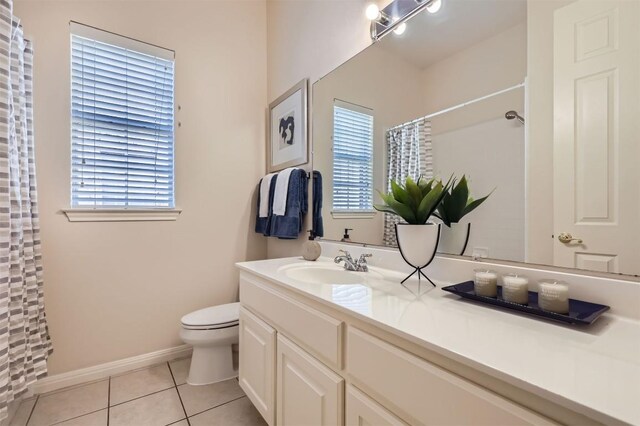 bathroom with tile patterned floors, toilet, a wealth of natural light, and vanity