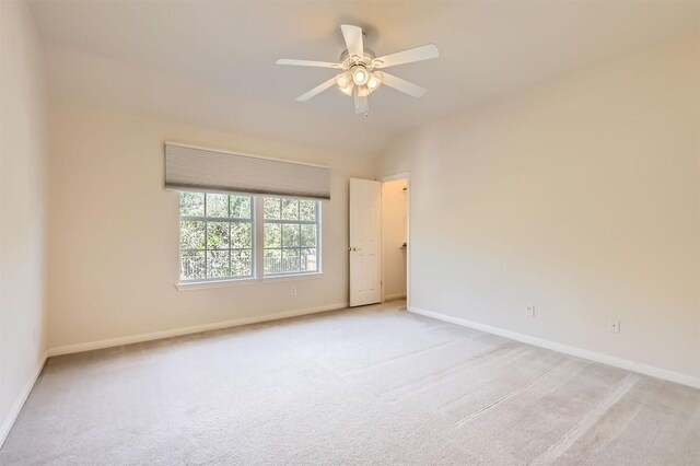 empty room featuring baseboards, light carpet, ceiling fan, and vaulted ceiling