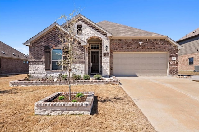 french country style house with a garage, stone siding, brick siding, and concrete driveway