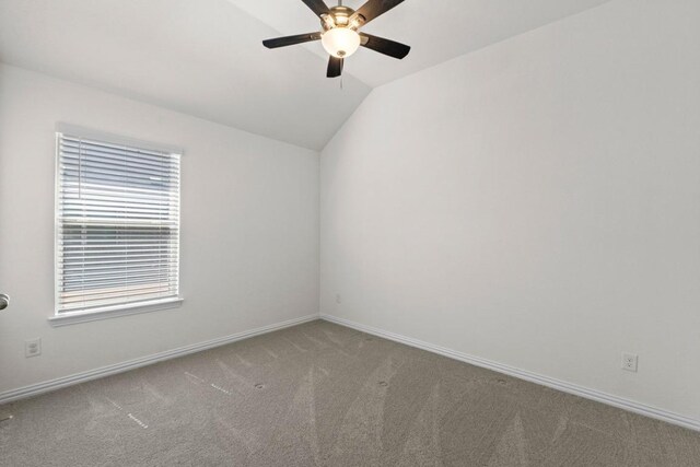 spare room featuring lofted ceiling, carpet flooring, baseboards, and ceiling fan