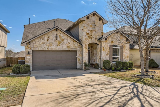 french country style house featuring a shingled roof, concrete driveway, a garage, and fence