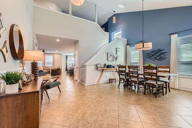 dining space featuring light tile patterned floors, high vaulted ceiling, and baseboards