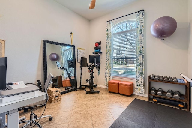 exercise area featuring light tile patterned floors, a ceiling fan, and baseboards