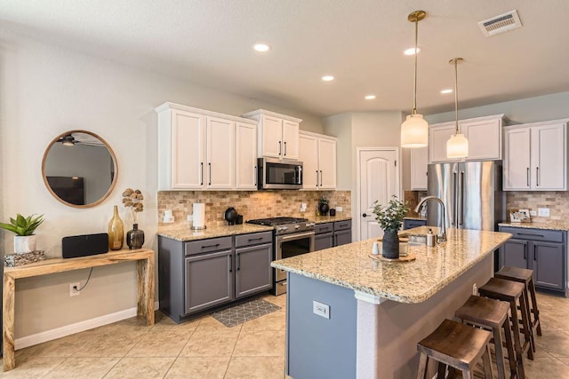 kitchen with light stone counters, visible vents, appliances with stainless steel finishes, and gray cabinetry