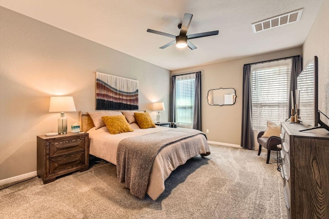 carpeted bedroom with visible vents, baseboards, and ceiling fan