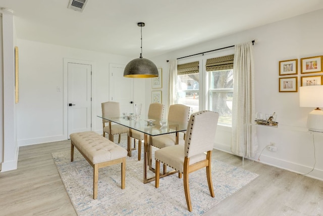 dining space featuring visible vents, baseboards, and light wood finished floors