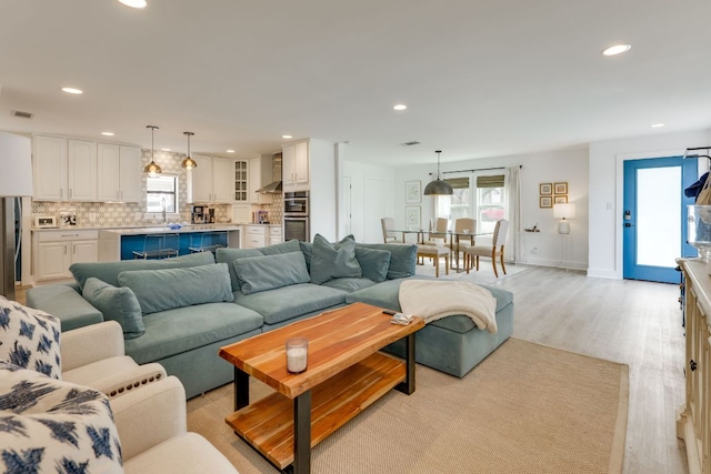 living room featuring recessed lighting, baseboards, and light wood-style floors