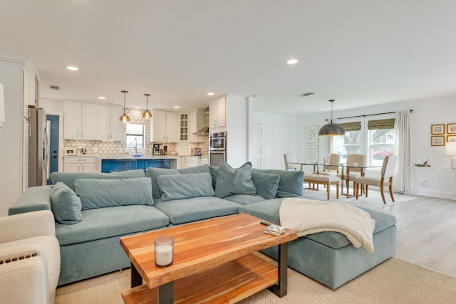 living area featuring recessed lighting, visible vents, light wood finished floors, and baseboards