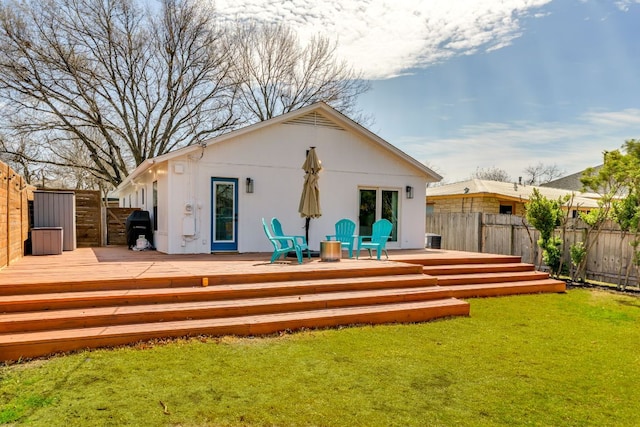 rear view of house featuring a deck, a yard, and fence