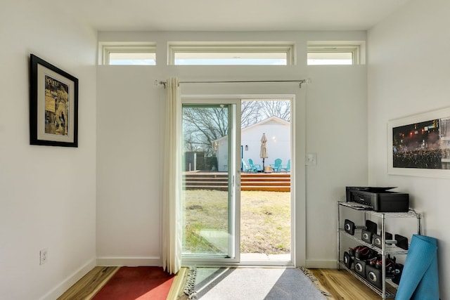 doorway featuring baseboards and wood finished floors