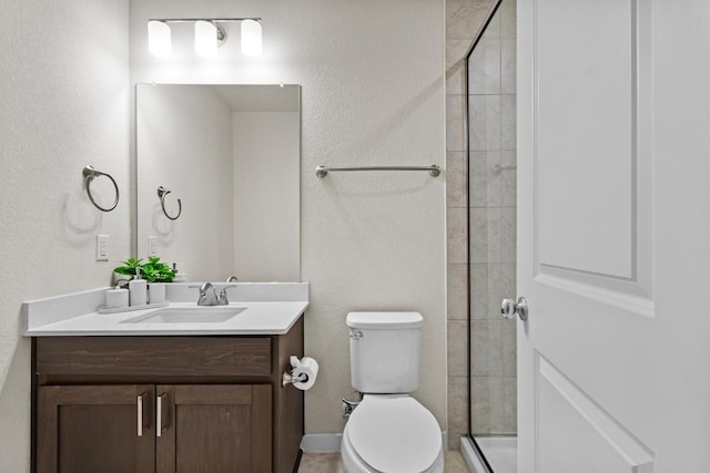 full bathroom with tiled shower, toilet, vanity, and a textured wall