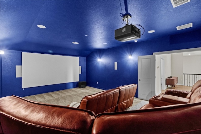 carpeted home theater featuring visible vents, baseboards, a textured ceiling, and vaulted ceiling