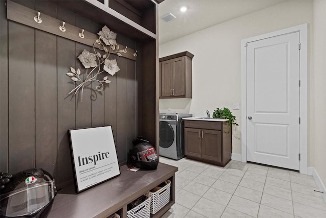 laundry room featuring a sink, cabinet space, light tile patterned flooring, baseboards, and washer / dryer