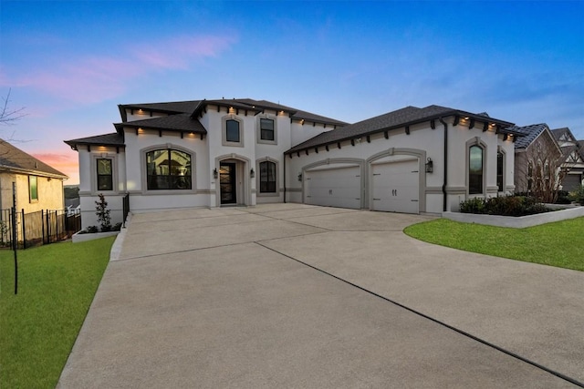 mediterranean / spanish home with fence, concrete driveway, a front yard, stucco siding, and a garage