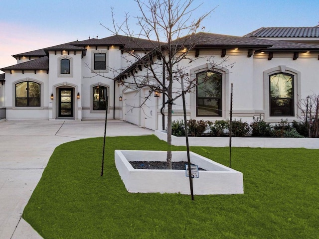 view of front of house featuring a front lawn, a garage, and stucco siding