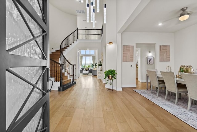 entrance foyer featuring visible vents, wood-type flooring, a high ceiling, baseboards, and stairs