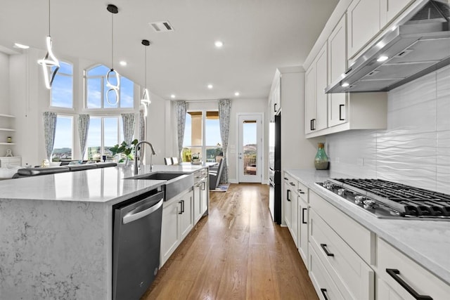 kitchen featuring visible vents, a sink, appliances with stainless steel finishes, white cabinets, and extractor fan