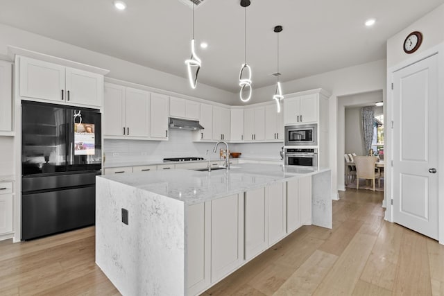 kitchen with backsplash, black appliances, light wood-style flooring, white cabinetry, and a sink