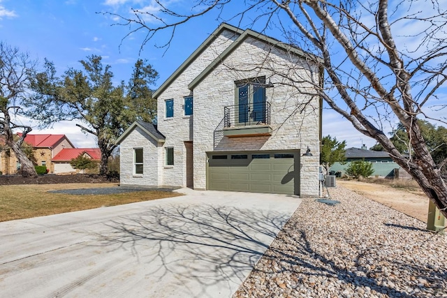 view of front facade with concrete driveway, a balcony, an attached garage, and stone siding