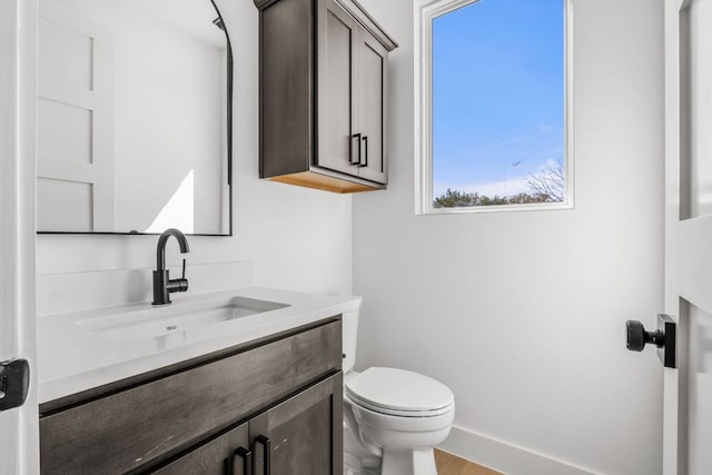 bathroom featuring toilet, vanity, and baseboards