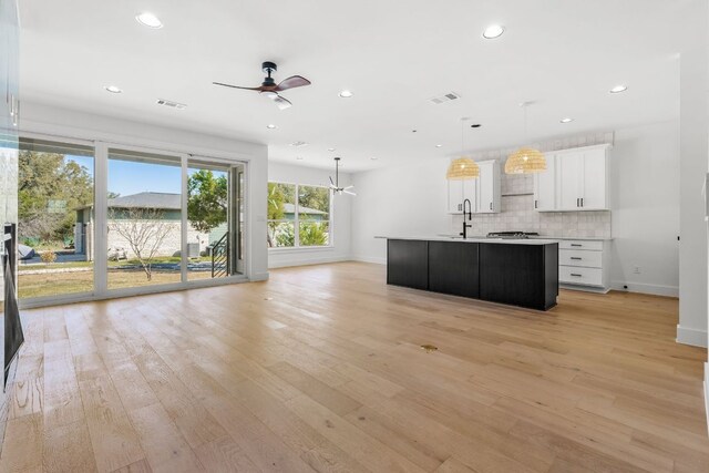 kitchen with light wood-style flooring, visible vents, open floor plan, and ceiling fan with notable chandelier