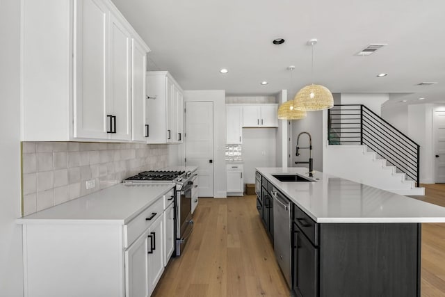 kitchen featuring visible vents, appliances with stainless steel finishes, light wood-style floors, white cabinetry, and a sink