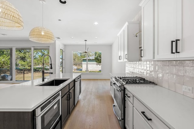 kitchen with a sink, stainless steel appliances, tasteful backsplash, and light countertops