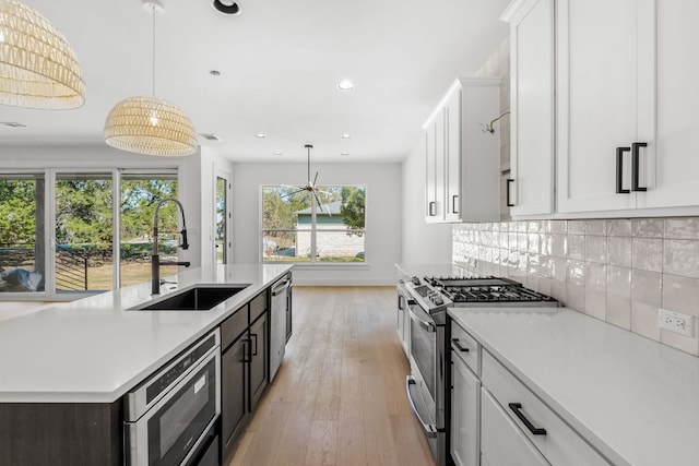 kitchen with white cabinetry, stainless steel appliances, light countertops, and a sink