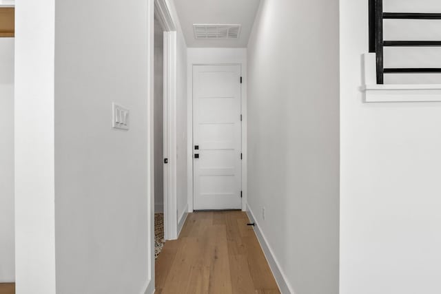 hallway with visible vents, baseboards, and wood finished floors