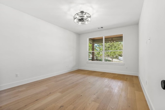 spare room featuring visible vents, light wood-style flooring, and baseboards