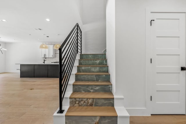 staircase with recessed lighting, wood finished floors, visible vents, and baseboards