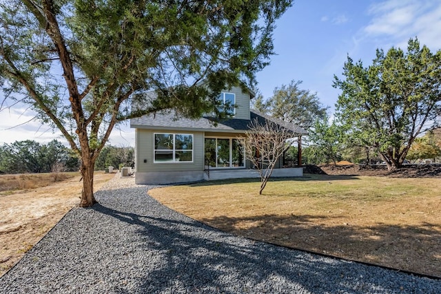 back of property with a yard and a shingled roof