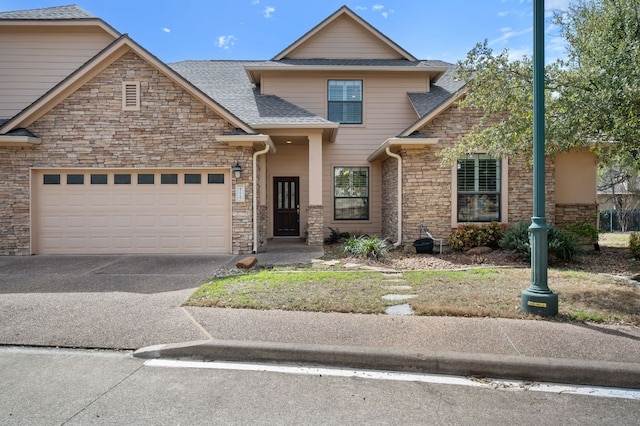 view of front of home featuring an attached garage, stone siding, driveway, and a shingled roof