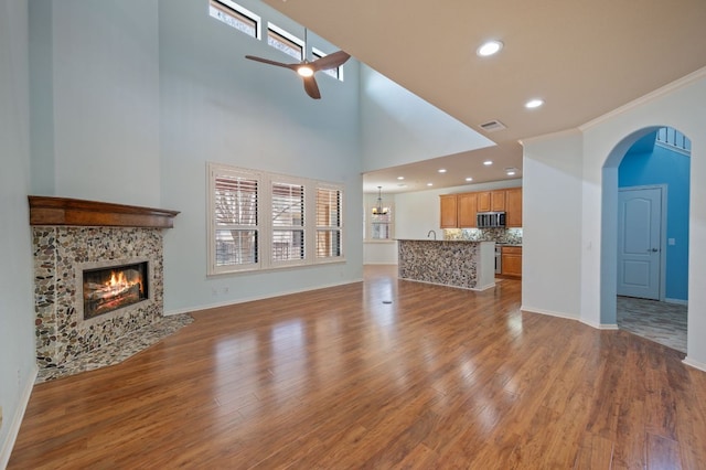 unfurnished living room featuring wood finished floors, a fireplace with flush hearth, a ceiling fan, and visible vents