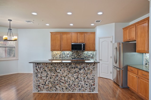 4229 Johns Light Dr, Austin, TX 78727 - kitchen featuring stainless steel appliances, wood finished floors, backsplash, recessed lighting, and a kitchen island with sink