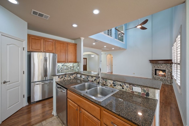 4229 Johns Light Dr, Austin, TX 78727 - kitchen with stainless steel appliances, a sink, a ceiling fan, arched walkways, and brown cabinets