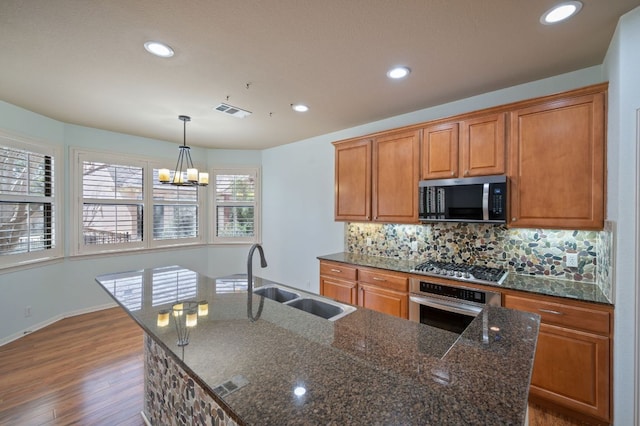4229 Johns Light Dr, Austin, TX 78727 - kitchen featuring appliances with stainless steel finishes, a sink, a chandelier, wood finished floors, and a kitchen island with sink