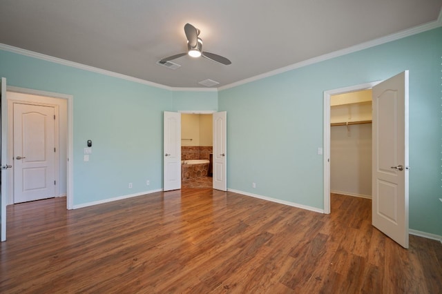 unfurnished bedroom featuring visible vents, a spacious closet, wood finished floors, and crown molding