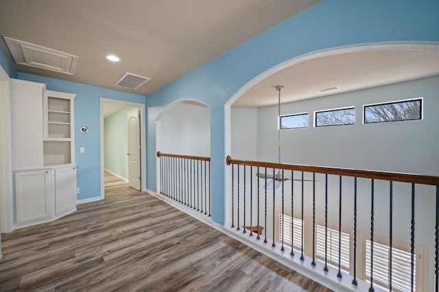 hallway with attic access, recessed lighting, wood finished floors, and visible vents