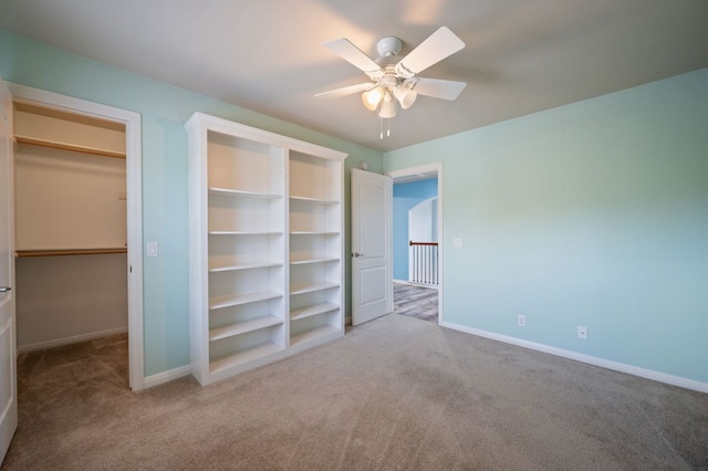 unfurnished bedroom with a spacious closet, ceiling fan, baseboards, and carpet floors