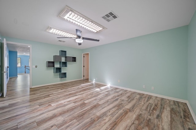 spare room with ceiling fan, visible vents, baseboards, and wood finished floors