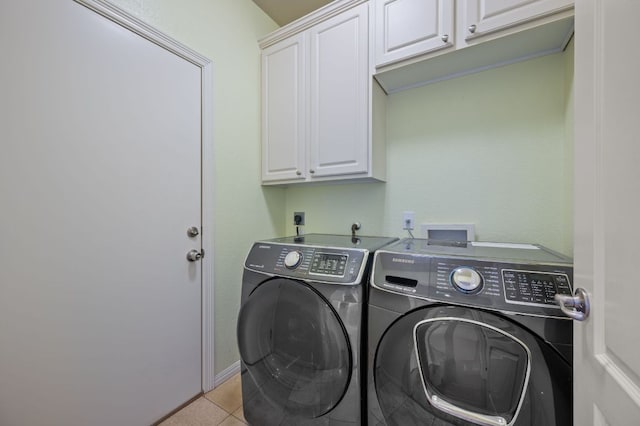 laundry room with light tile patterned floors, baseboards, cabinet space, and washing machine and dryer