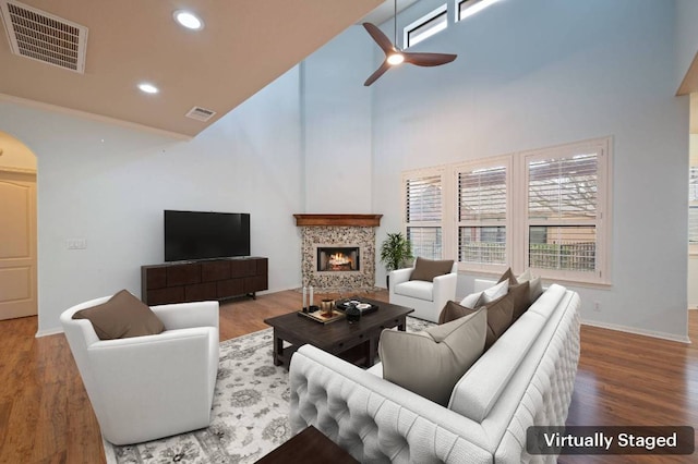 4229 Johns Light Dr, Austin, TX 78727 - living area featuring a towering ceiling, arched walkways, a ceiling fan, a tiled fireplace, and baseboards
