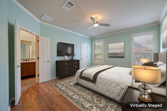 bedroom with a sink, visible vents, wood finished floors, and ornamental molding