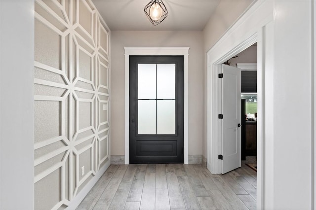 doorway to outside featuring light wood-type flooring, baseboards, and a healthy amount of sunlight