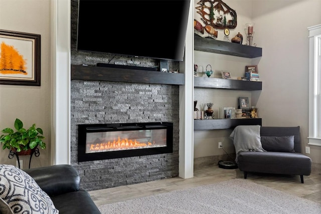 living area featuring a stone fireplace and wood finished floors